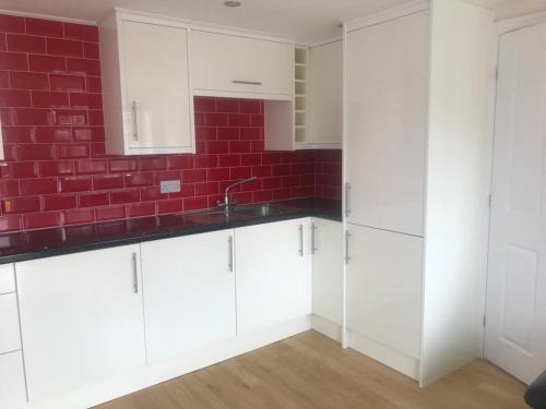 a kitchen with white cabinets and a red brick wall at Garden flat near the University of York in York