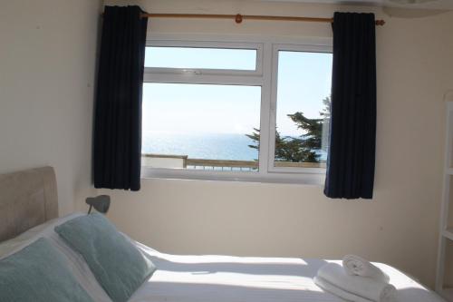 a bedroom with a window with a view of the ocean at Beach View - Mount Brioni in Downderry