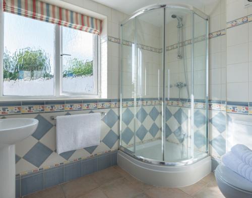 a bathroom with a shower and a tub and a sink at Polmorla in Polzeath