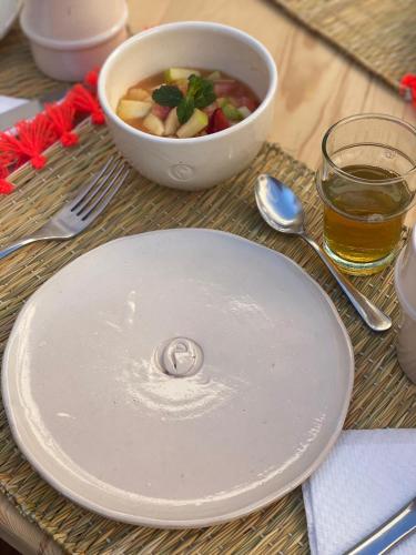 a plate with a bowl of fruit and a bowl of juice at Riad Gasämbre Touareg in Marrakech