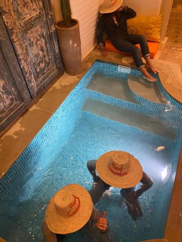a group of people in hats sitting in a swimming pool at Riad Gasämbre Touareg in Marrakech