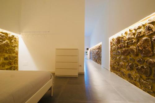 a bedroom with a bed and a wall with rocks at Kiwi in Latina