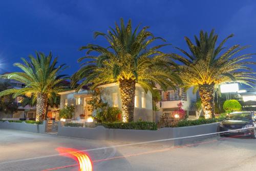 a group of palm trees in front of a building at Kapsohora Inn in Pefkohori