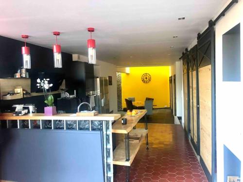 une cuisine avec des armoires noires et un mur jaune dans l'établissement Loft atypique 192m2, terrasse, aux portes de Lille, à Roubaix