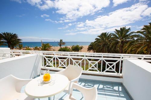 een balkon met een tafel en stoelen en het strand bij Hipotels La Geria in Puerto del Carmen