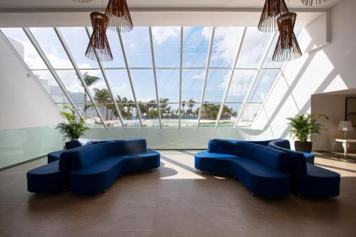 a large room with blue chairs and a large window at Hipotels La Geria in Puerto del Carmen