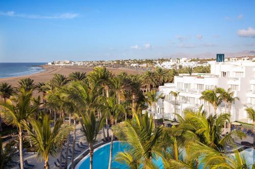an aerial view of the beach and buildings and palm trees at Hipotels La Geria in Puerto del Carmen
