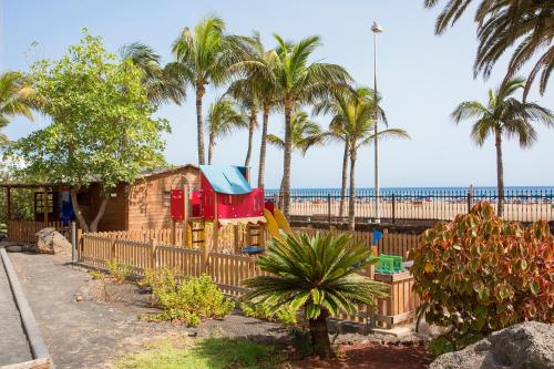 a playground next to a beach with palm trees at Hipotels La Geria in Puerto del Carmen
