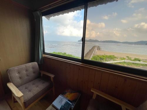 a window with a chair and a view of the ocean at 大砂荘 OZUNA CAMP and LODGE in Kaiyo