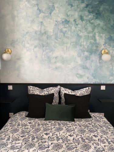 a bed with two pillows in front of a painting at La Suite Dandy - Beau T2 -Terrasse, Parking gratuit, Climatisation in Bagnères-de-Bigorre