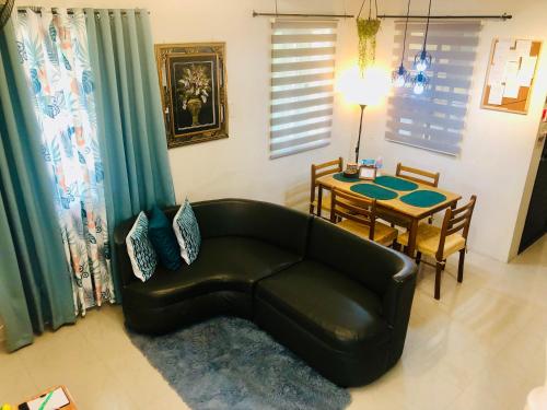 a living room with a black leather couch and a table at Downtown Prominenza 844 in Baliuag