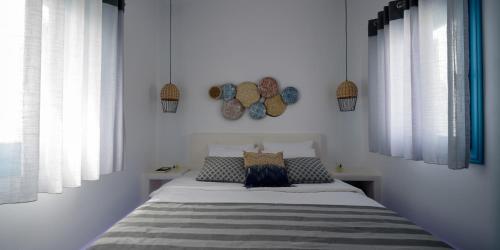 a bedroom with a bed with white walls and windows at Kalestesia Suites in Akrotiri