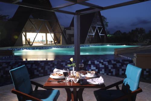 a table with food and drinks on a patio with a pool at Jagira Ananta Elite , Sasan Gir in Chitrod