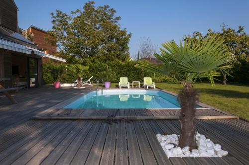 a swimming pool on a wooden deck with a palm tree at Le Lagon in Jargeau
