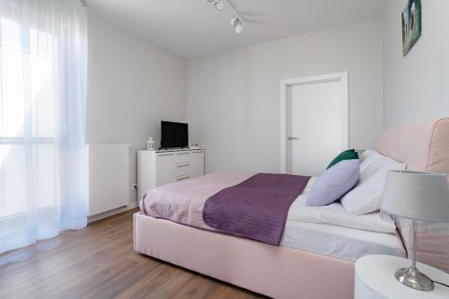 a white bedroom with a bed and a tv at INA Rent - Nadmorski Dwór in Gdańsk