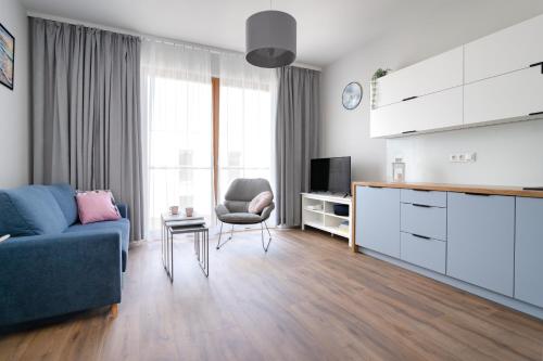 a living room with a blue couch and a tv at INA Rent - Nadmorski Dwór in Gdańsk
