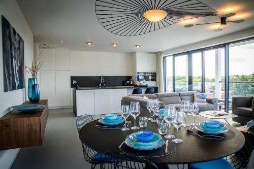 a dining room and living room with a table and chairs at Rots in de Branding Luxurious 2 bedroom apartment in the dunes with sea sight in Cadzand
