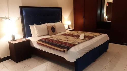 a large bed in a hotel room with two lamps at Hotel Royal Defence in Lahore