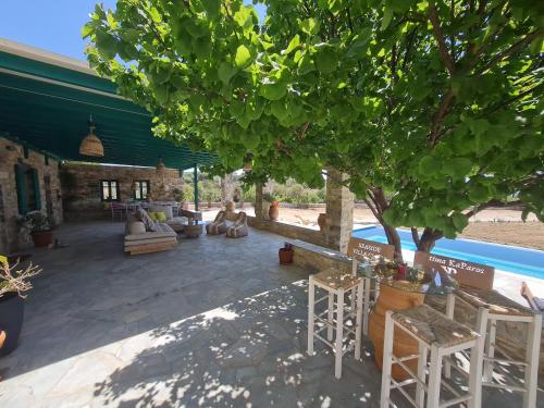 a patio with chairs and a tree next to a pool at seaside Ktima KaParos PAROS in Drios