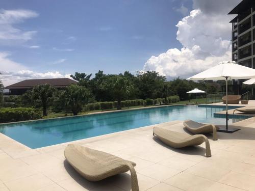 a swimming pool with two chairs and an umbrella at Sea Breeze Verandas at Anvaya Cove Penthouse Unit with Complete Sea View in Morong