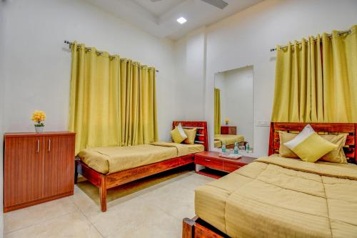 a bedroom with two beds and yellow curtains at IT'S HOME in Aurangabad