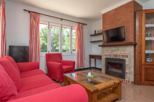 a living room with red furniture and a fireplace at Es Pins in Font de Sa Cala