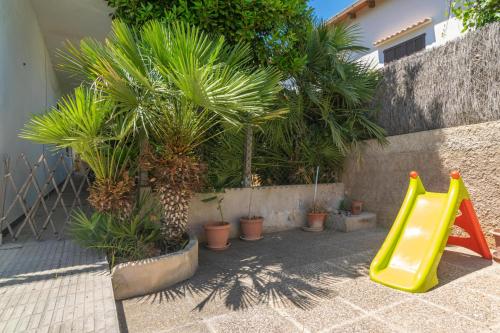a playground with a yellow slide and palm trees at Es Pins in Font de Sa Cala