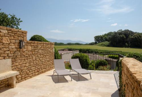 two chairs on a patio next to a stone wall at Domaine de Montine Chambres de Charme in Grignan