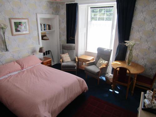 a bedroom with a bed and chairs and a window at Athollbank Guest House in Dundee