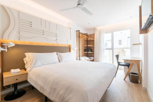a bedroom with a large white bed and a desk at Senator Cala Millor in Cala Millor