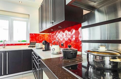 a kitchen with black cabinets and red tiles at Unique Sea & Sunset Residence in Ixia
