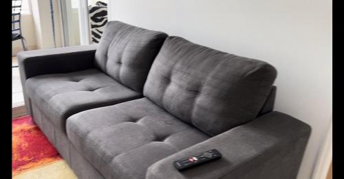 a gray couch with two remote controls on it at Departamento Cochoa Reñaca Viña del Mar Primera Línea de Playa in Viña del Mar