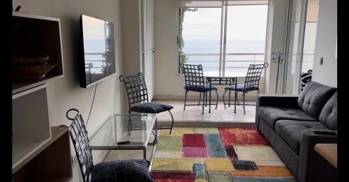 a living room with a couch and a table and chairs at Departamento EUROMARINA I para parejas primera línea de playa in Viña del Mar