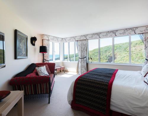 Un dormitorio con una cama y una silla y ventanas. en Egloskerry, en Wadebridge