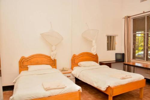 a bedroom with two beds and a window at MAKERERE UNIVERSITY GUEST HOUSE in Kampala