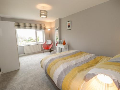 a bedroom with a bed and a red chair at Hudolfa in Menai Bridge