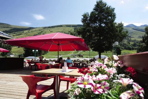 a table with a red umbrella and some flowers at Hôtel Les 2 Alpes L'Orée Des Pistes in Les Deux Alpes
