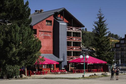 a woman walking past a building with pink umbrellas at Hôtel Les 2 Alpes L'Orée Des Pistes in Les Deux Alpes