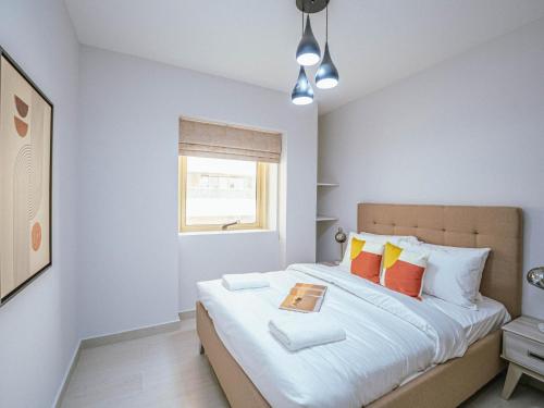 a bedroom with a bed with white sheets and orange pillows at Beautifully Decorated & Homely 2 Bed apartment in Dubai