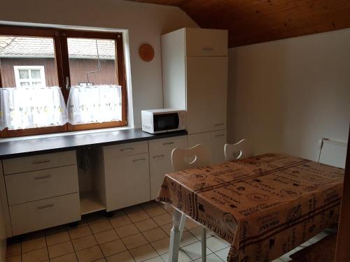 eine Küche mit einem Tisch, einer Mikrowelle und einem Fenster in der Unterkunft Entspannt mit Hund in Schönwald