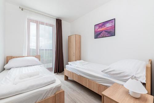 two twin beds in a room with a window at Hérics Apartman in Tihany