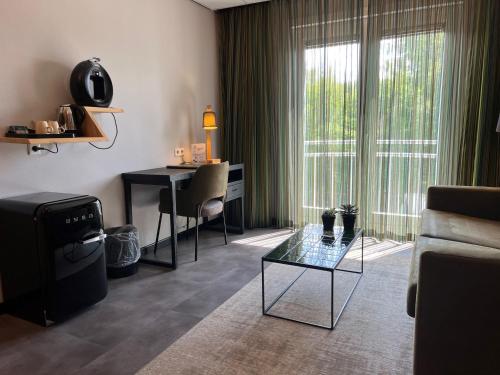 a living room with a glass table and a desk at ´t Wapen van Marion in Oostvoorne