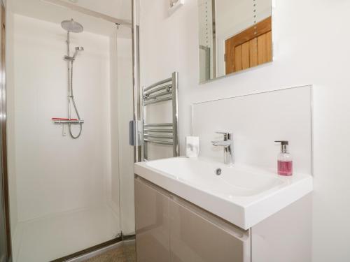 a white bathroom with a sink and a shower at Gwel Nans in St. Agnes
