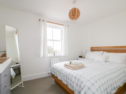 a bedroom with a bed with a window and a mirror at Gwel Nans in St. Agnes