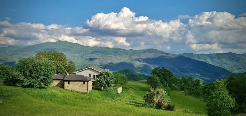 una casa en una colina con montañas en el fondo en Agriturismo Il Noce d'Oro, en Borgo Val di Taro