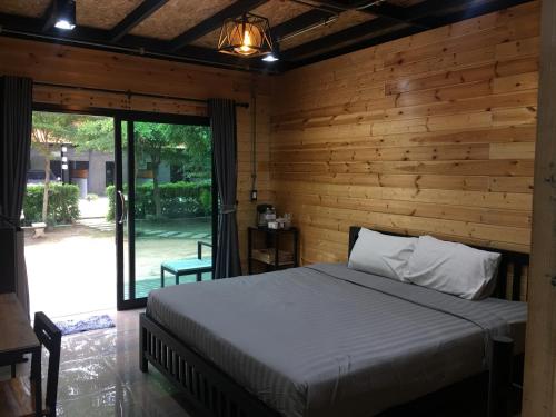 a bedroom with a bed and a wooden wall at The Loft Resort Kabin Buri in Kabin Buri