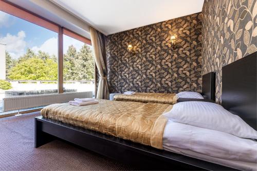 a bedroom with a bed and a large window at Apartamentai Auska in Palanga