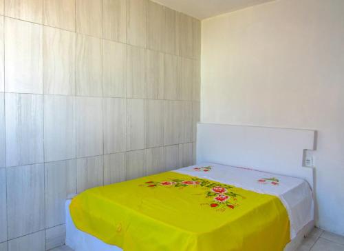 a room with a bed with a yellow blanket at Casa com Piscina e Churrasqueira em Vera Cruz BA in Barra Grande