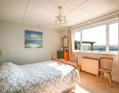 a bedroom with a bed and a chair and a window at Little Strand in Padstow