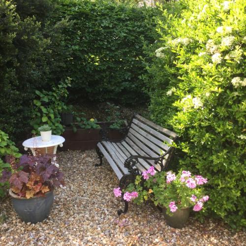 a park bench and a table and some flowers at Dwynant - A Room with a View in Llangathen